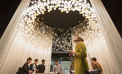 A women stands under an event lighting setup.